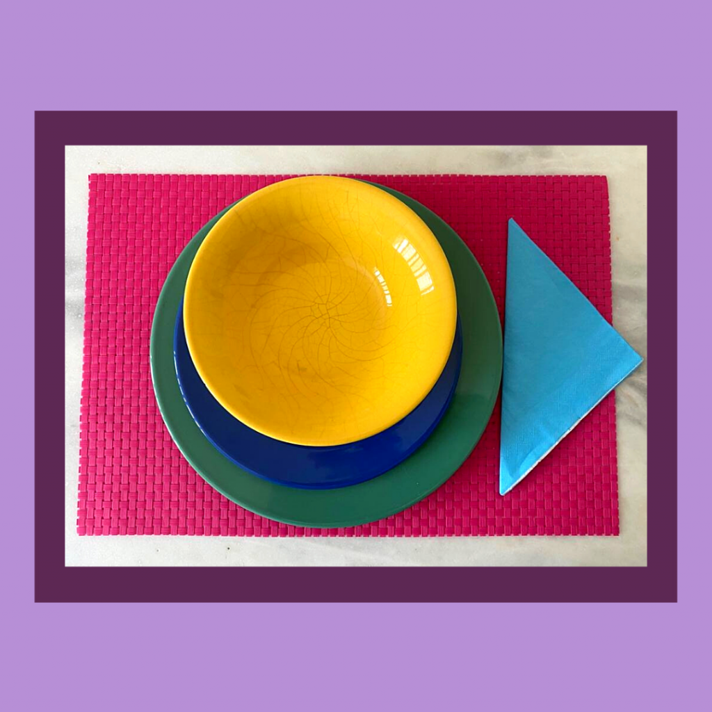 Base rosa, prato raso verde, prato de sopa amarelo, sobremesa azul e guardanapo azul.
